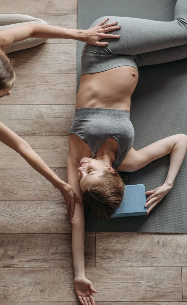 Pregnant woman practicing yoga with trainer, focused on relaxation and stretching, indoors.